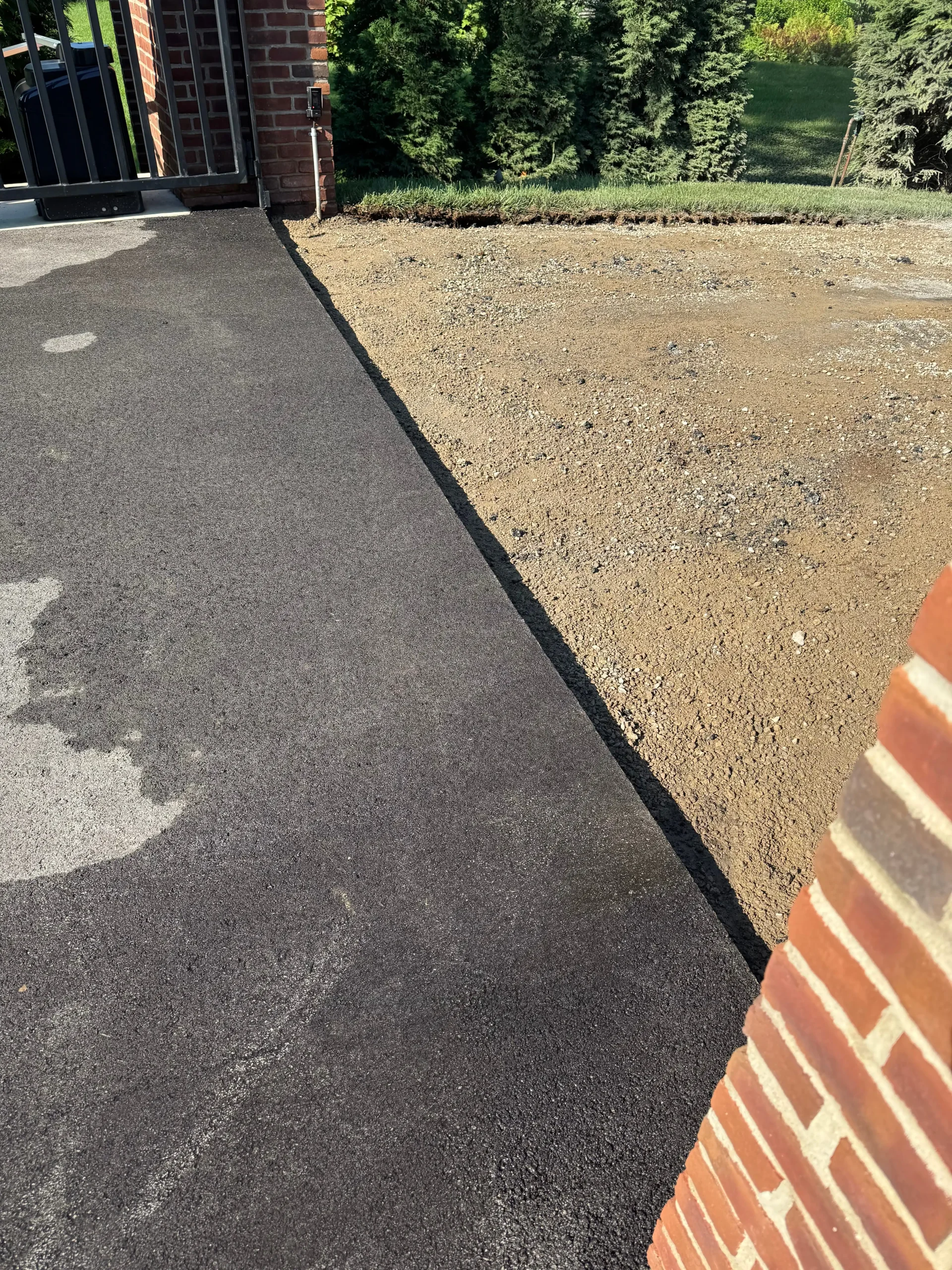 The existing asphalt near the rear of the residence, which was not part of the repair, shown alongside the adjacent section excavated and prepped for repaving.
